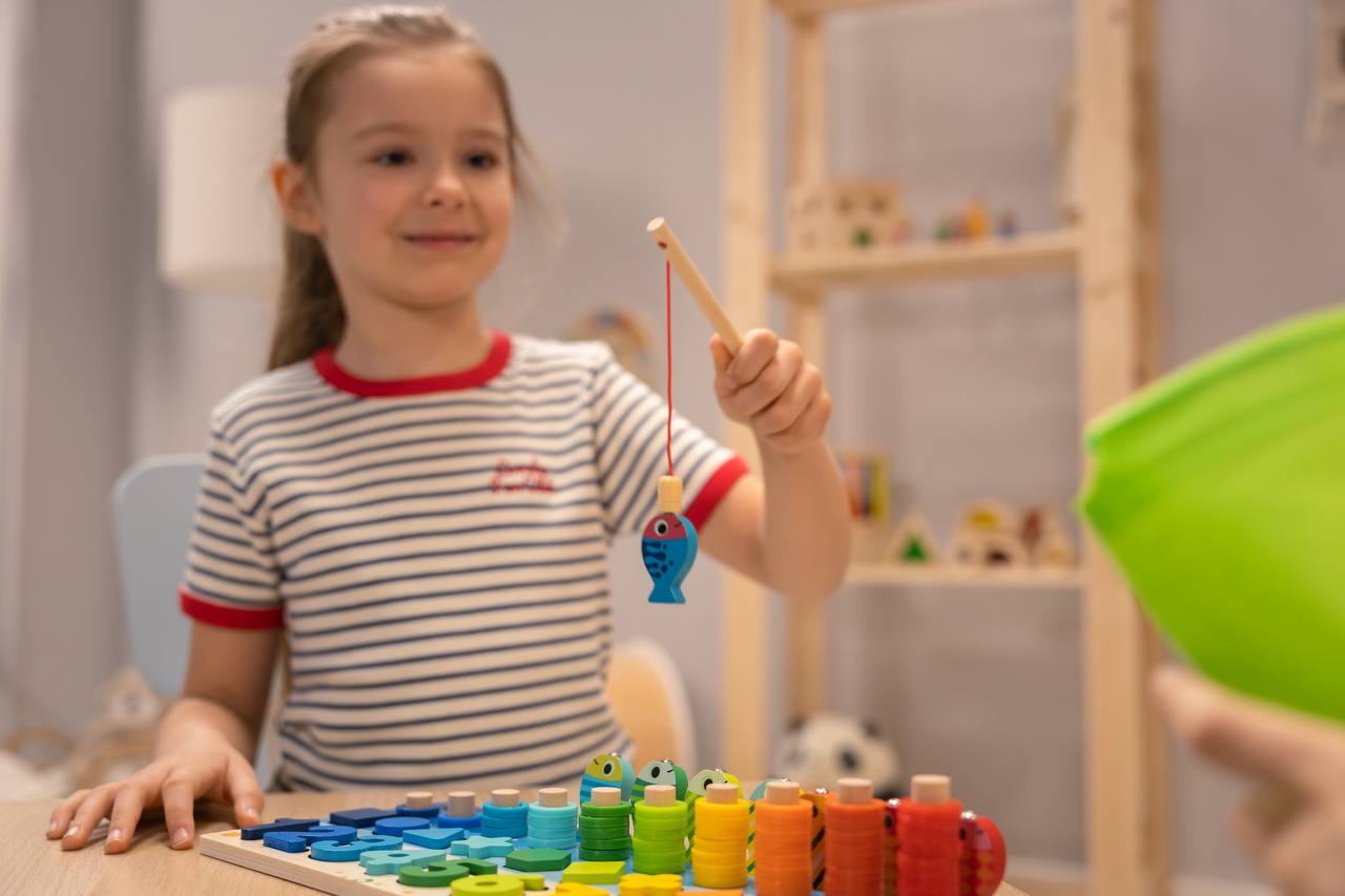 Mädchen spielt begeistert mit dem Montessori Angelspiel aus Holz