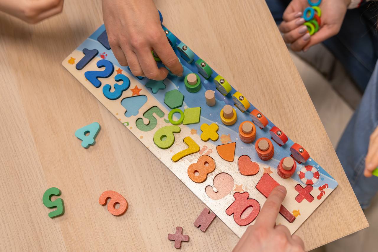 Kinderhände spielen mit der magnetischen Holzangel und Fischen